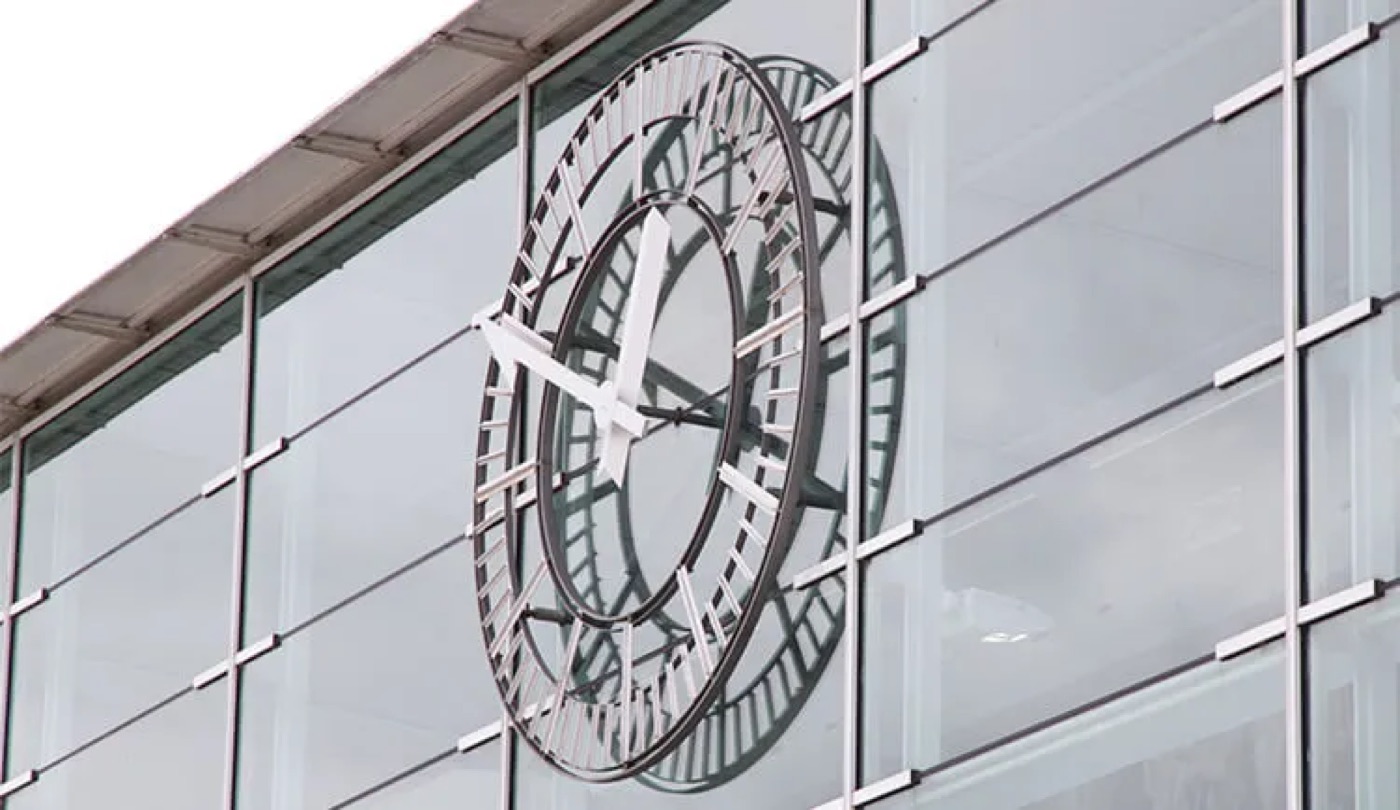 Skeleturskive med visere og timemarkører monteret direkte på facaden